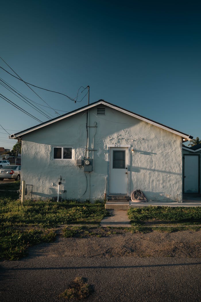 Small white suburban house with sunny exterior and vibrant blue sky.